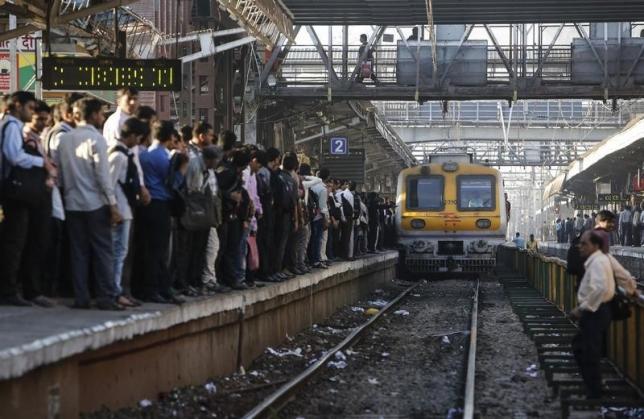 Commuters wait on a crowded railway platform as a train enters a suburban station in Mumbai
