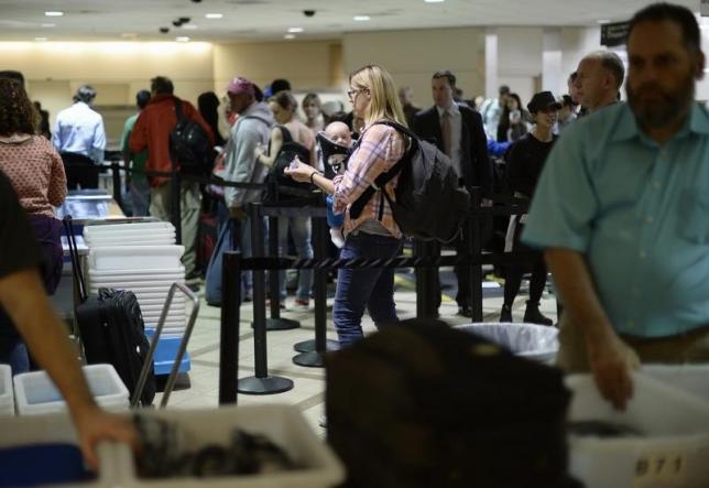 An airline passenger and her baby wait in line before passing through TSA security checkpoint at Los Angeles International Airport