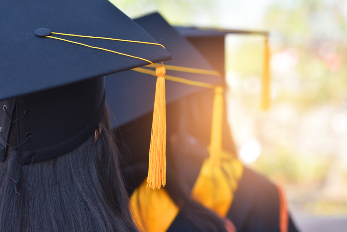 The back image of the graduates wearing a yellow tassel hat.