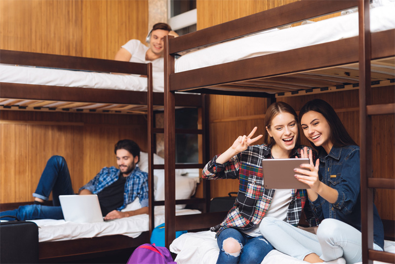 Girls sit on bed and talking on video at tablet.