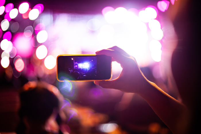People taking photographs with smart phone during Live music concert and crowd in background