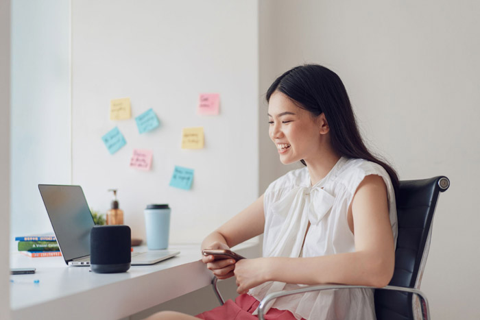 Young asian female working from home with smart assistant speaker