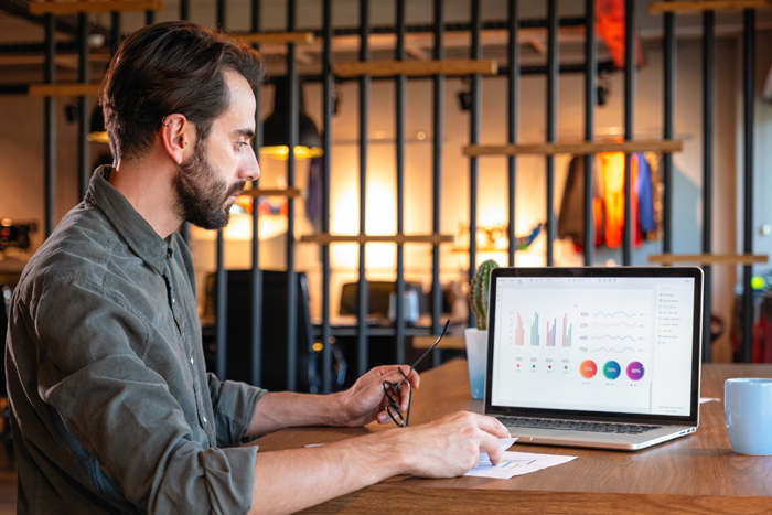 Handsome caucasian businessman working on the desk looking at graphs on laptop..