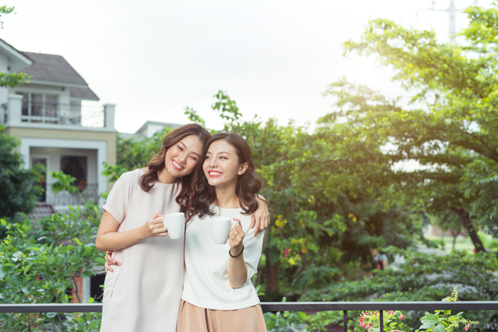 Happy young women friends well-dressed smiling while standing together