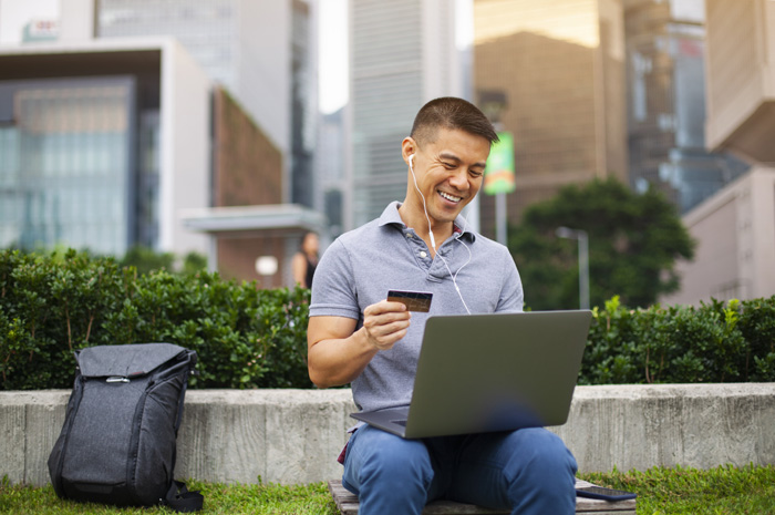 Asian man using credit card and laptop outdoors Hong Kong