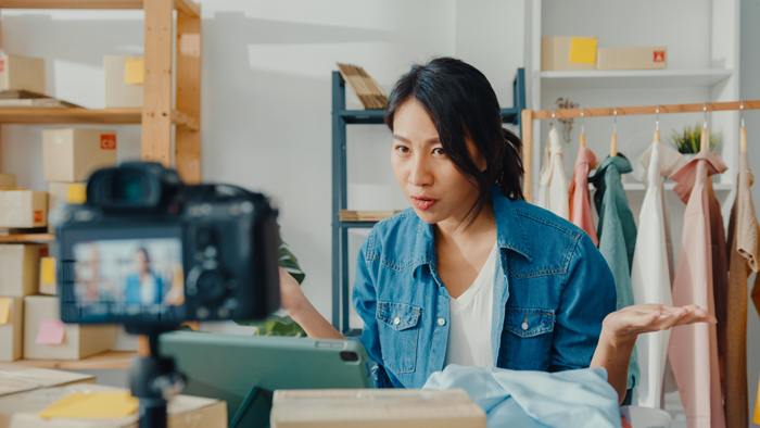 Young Asia lady fashion designer using mobile phone receiving pu